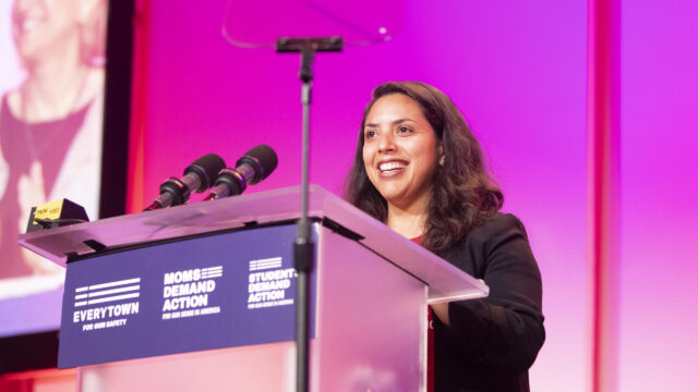 Alex Navarro stands smiling at a podium