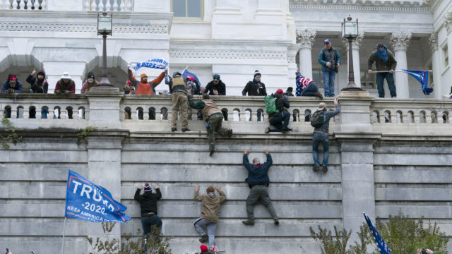 Supporters of President Donald Trump climb the west wall of the the U.S. Capitol