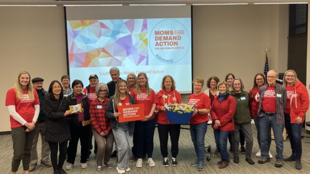 20 members of the Burnsville Care Team stand in front of a powerpoint slide that reads 