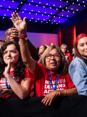 Volunteers stand and wave in the front row at the Presidential Gun Sense Forum