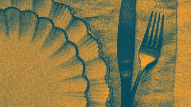 An orange- and blue-toned image of a scalloped dinner plate resting on a placemat; a knife and fork rest to the right of the plate edge.